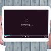 Persona che guarda uno streaming video interrotto dal buffering su laptop, con simbolo di caricamento sullo schermo